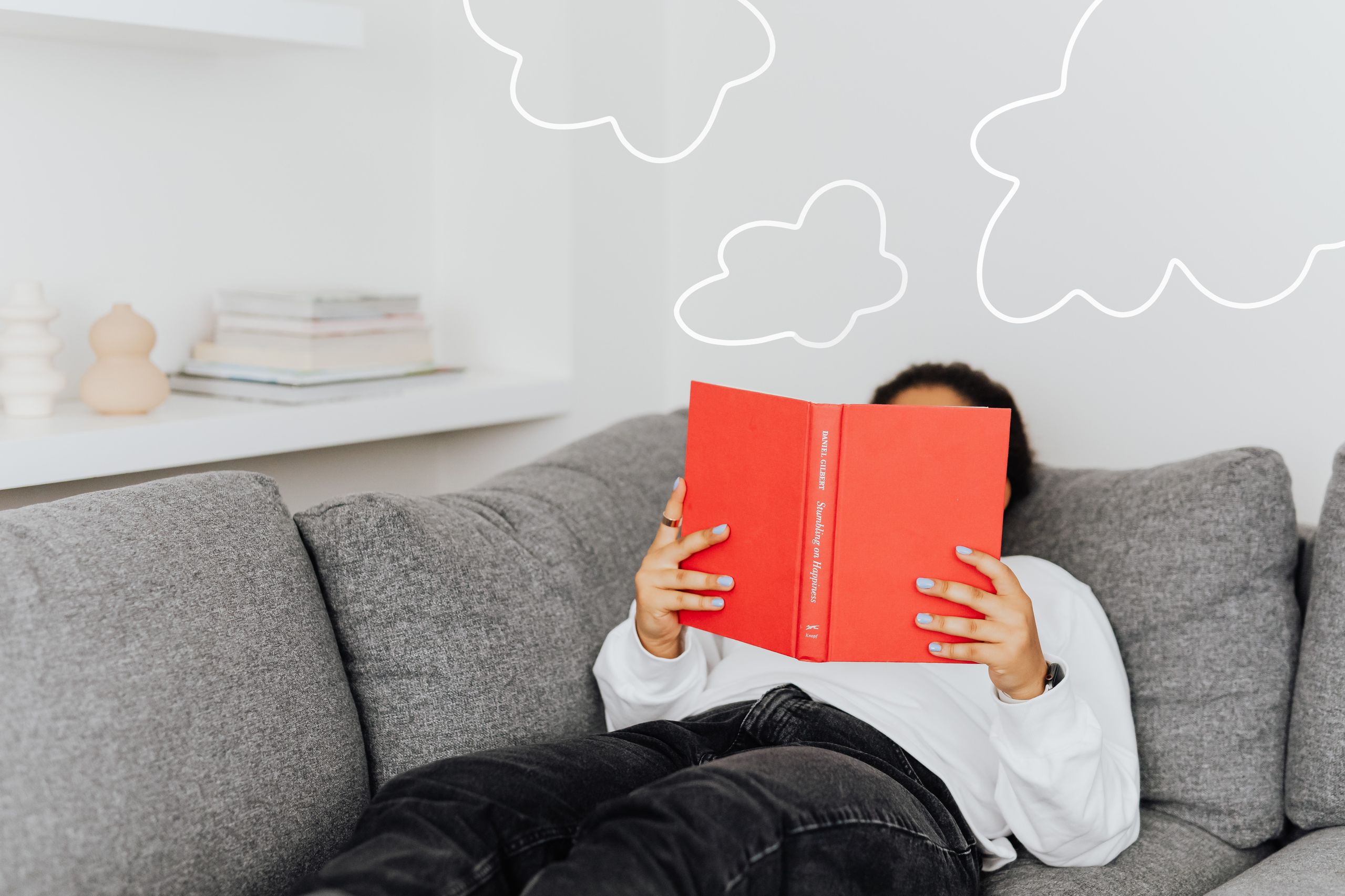 Человек лежит на диване с книгой — мысли проплывают облаками над головой
